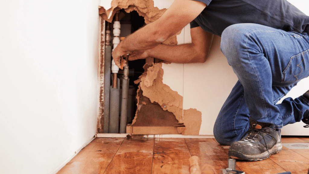 A man diligently repairs a hole in the wall, showcasing his handyman skills and attention to detail.