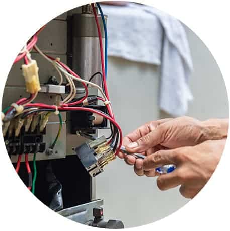 hands holding a screw driver next to wires