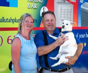 John with All Utah Plumbing with a happy customer and John is holding the customer's dog.