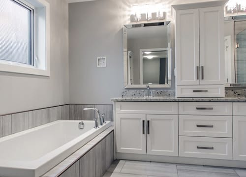 Bathroom showing a bathtub, sink, 2 mirrors, and drawers.