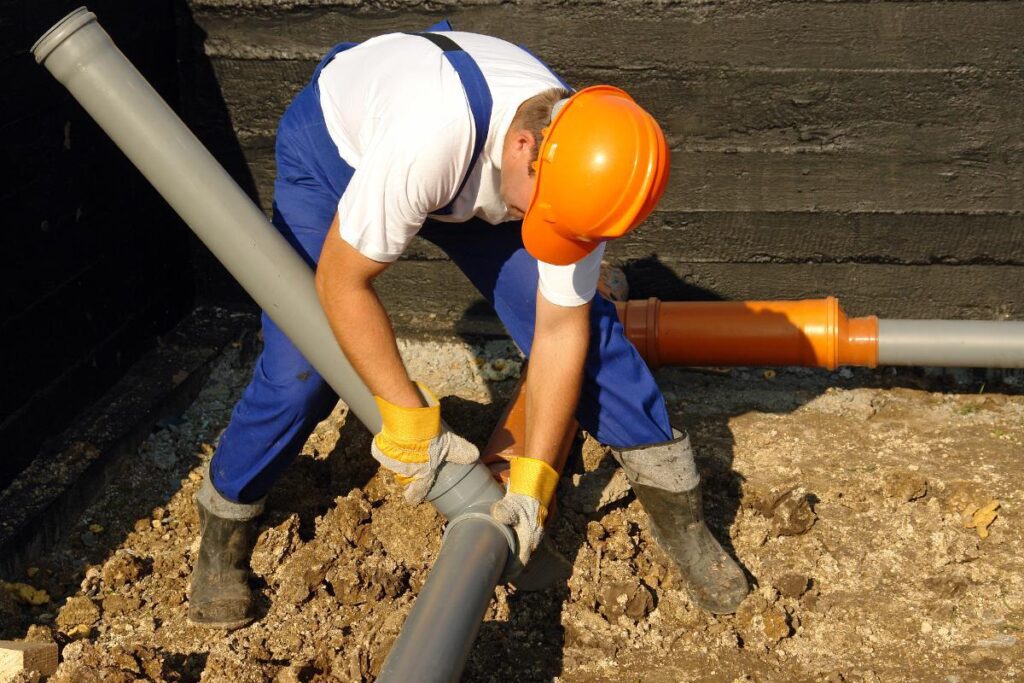 sewer line repair worker blue pant and orange helmet
