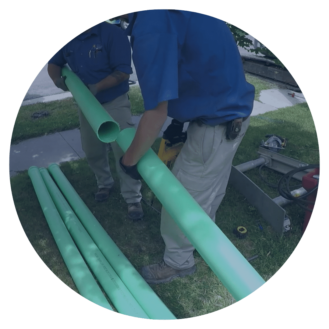 2 guys holding a green pipe working on a sewerline replacement