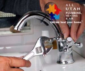 Two hands working on a silver kitchen or bathroom faucet. The right hand is holding a wrench and the left hand is holding the cold water knob.